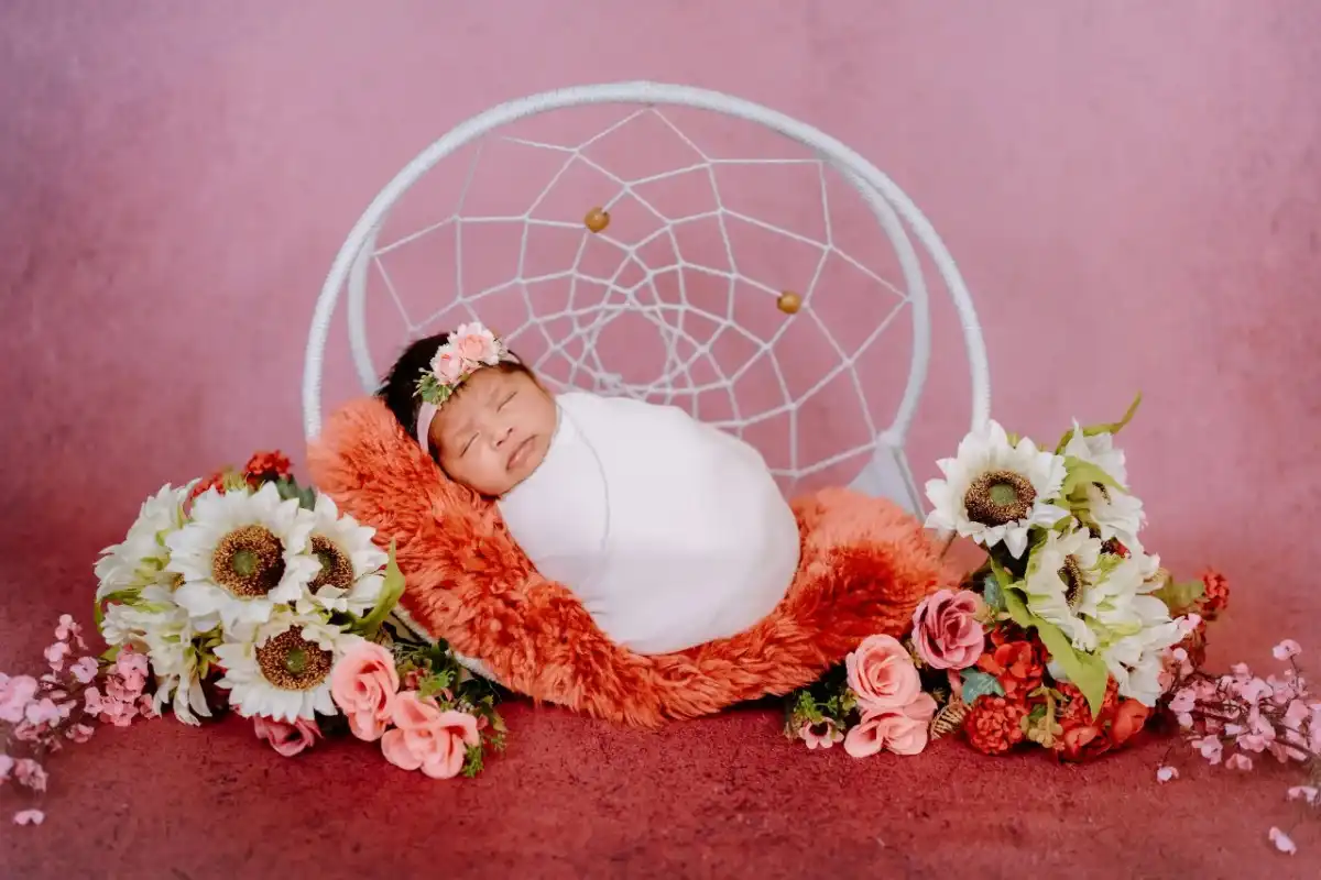 Sleeping baby surrounded by soft newborn photography props